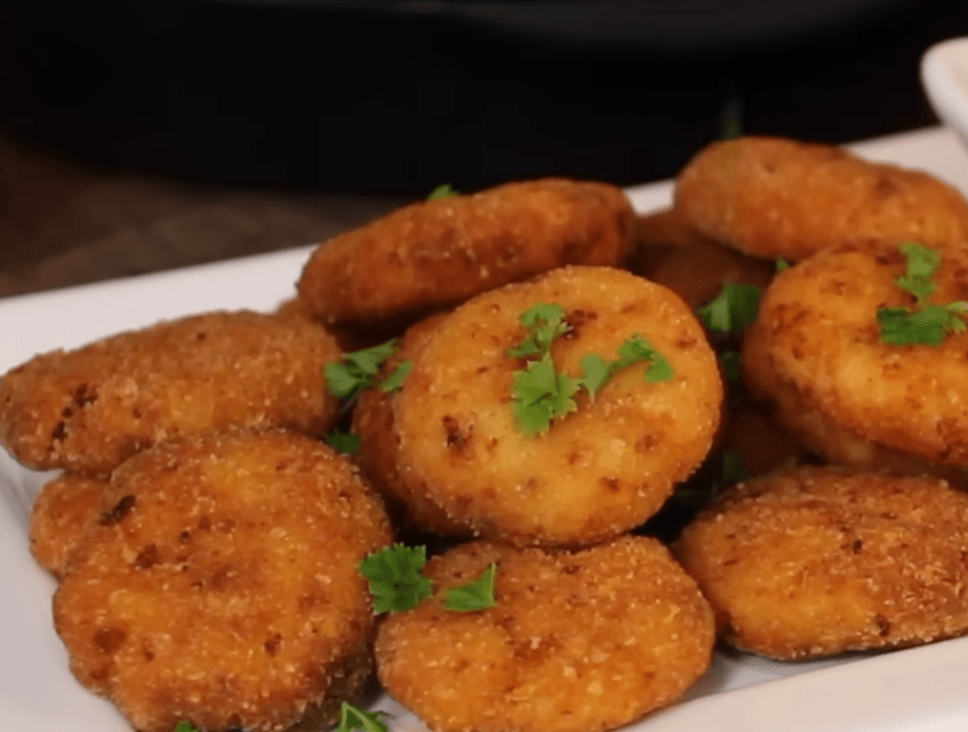A plate of crispy golden-brown homemade Brazilian chicken nuggets served with a side of dipping sauce